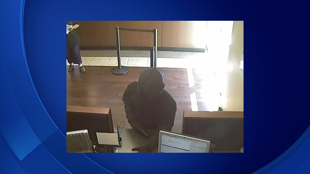 The FBI believes this man could be the "Filter Bandit" who is responsible for nine robberies across Broward County. In this photo, the robber demands money from a bank employee while brandishing a gun. (Source: FBI)