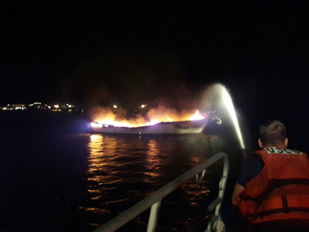 Petty Officer 2nd Class Justin Cravens, a crew member aboard a 45-foot Response Boat-Medium from Coast Guard Station Fort Myers Beach, Florida, responds to a sailboat explosion in Back Bay, Florida, Friday, Aug. 5, 2016. The sailboat came free from its mooring and caught another sailboat on fire. (U.S. Coast Guard photo by Seaman Kerry Doris)