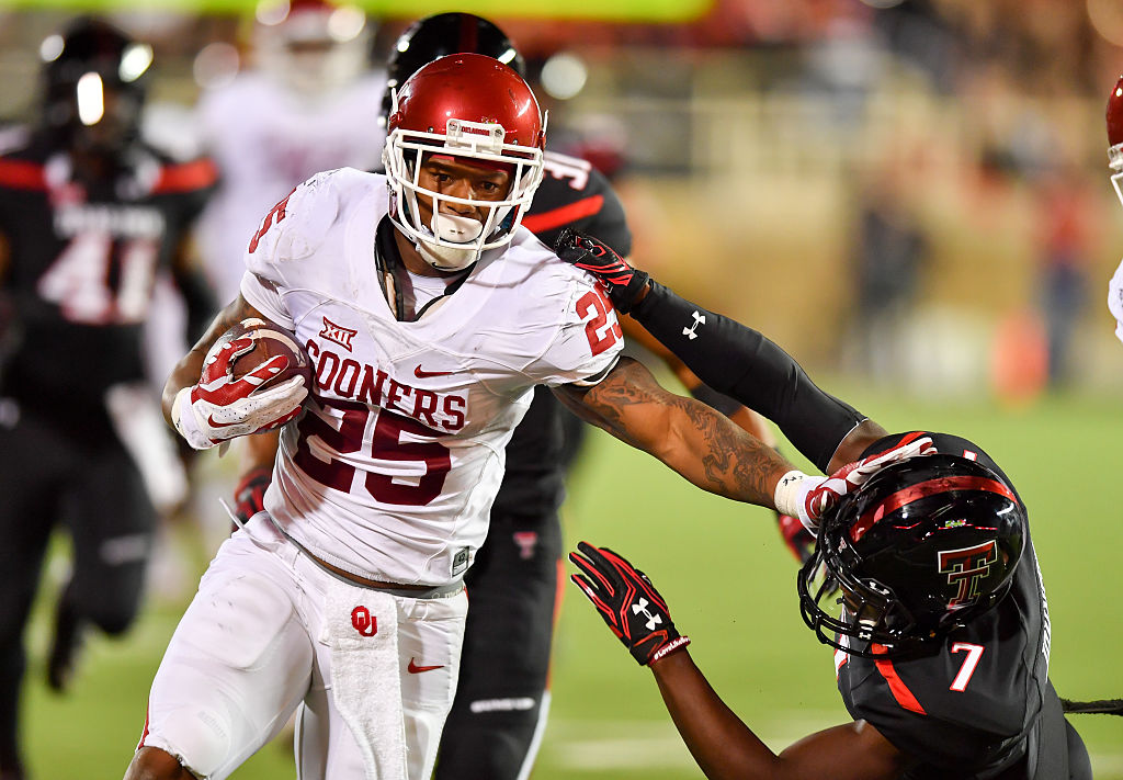 LUBBOCK, TX - OCTOBER 22: Joe Mixon #25 of the Oklahoma Sooners gets past Jah'Shawn Johnson #7 of the Texas Tech Red Raiders during the first half of the game between the Texas Tech Red Raiders and the Oklahoma Sooners on October 22, 2016 at AT&T Jones Stadium in Lubbock, Texas. (Photo by John Weast/Getty Images)